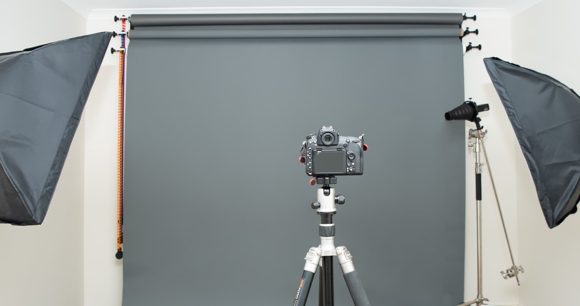 Chamara Perera Photography studio setup with gray backdrop, softboxes, and camera on tripod used for professional photography sessions, providing a comfortable and versatile environment for capturing high-quality photos.